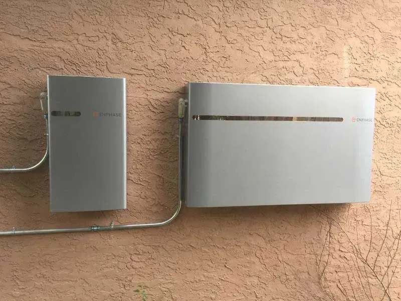 Two gray wall-mounted utility boxes with cables on a textured beige wall.