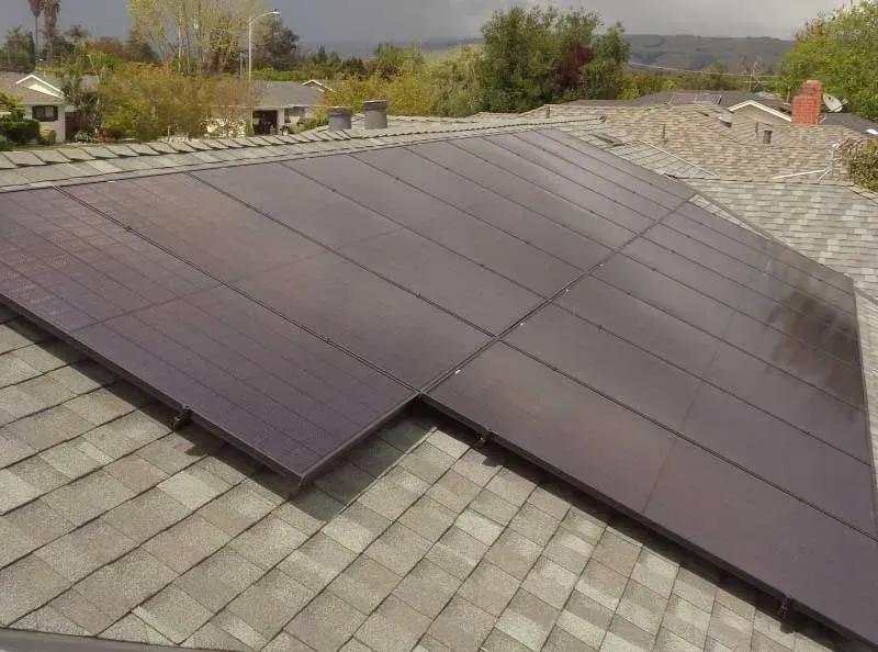 Solar panels mounted on a shingled rooftop under a clear sky
