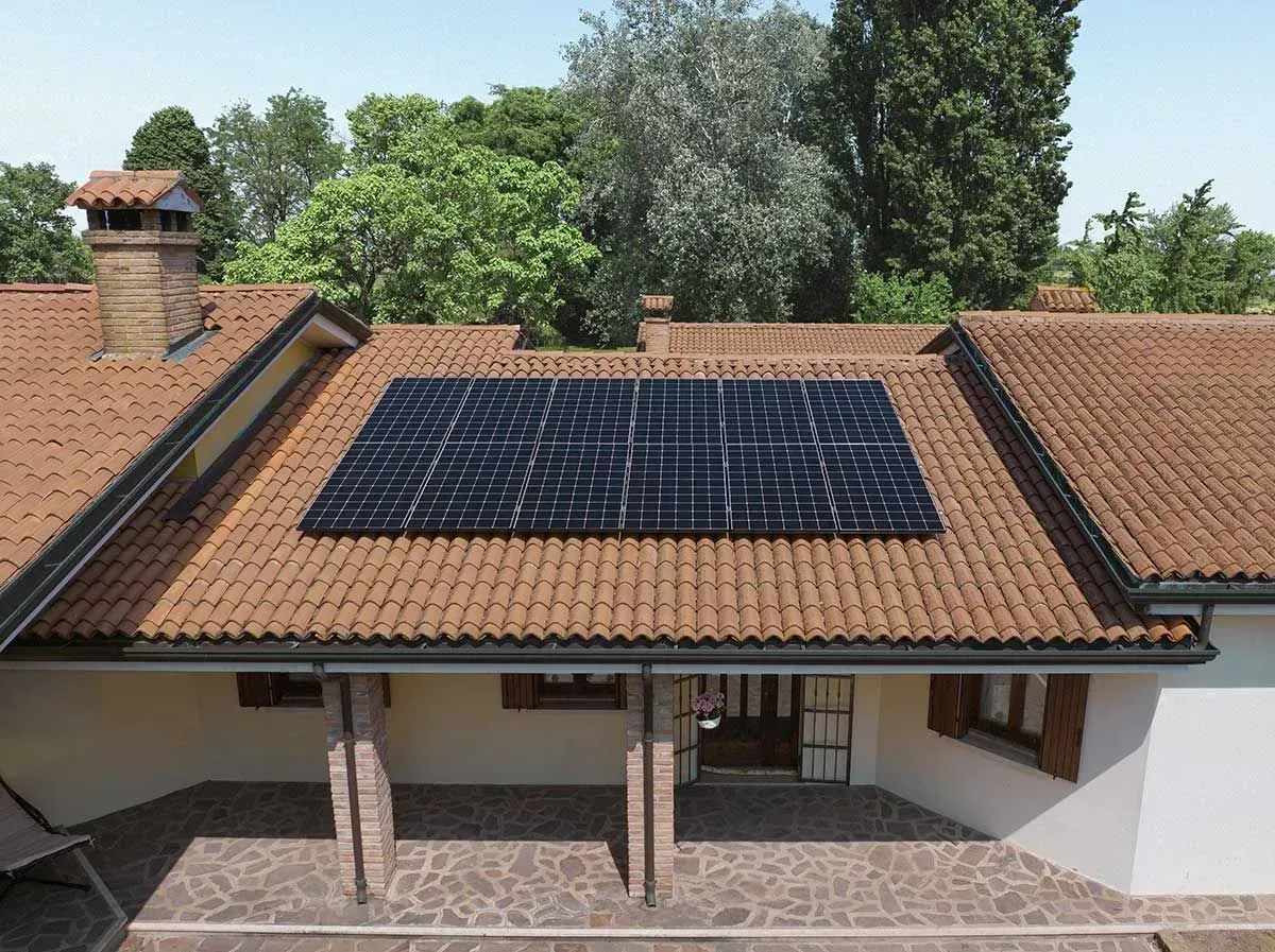 House with red tile roof and rooftop solar panels under trees