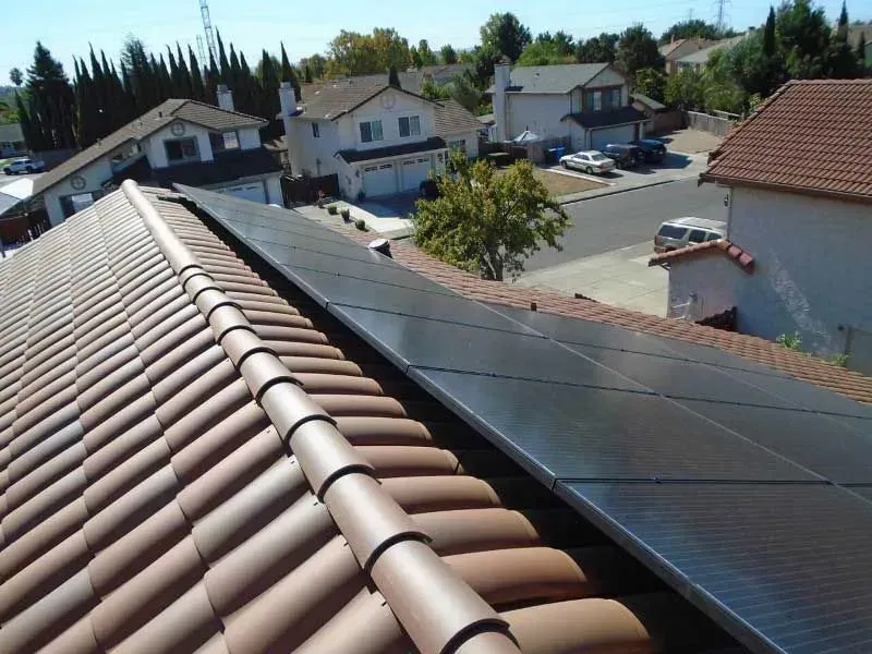 Residential rooftop with terracotta tiles and solar panels overlooking a neighborhood