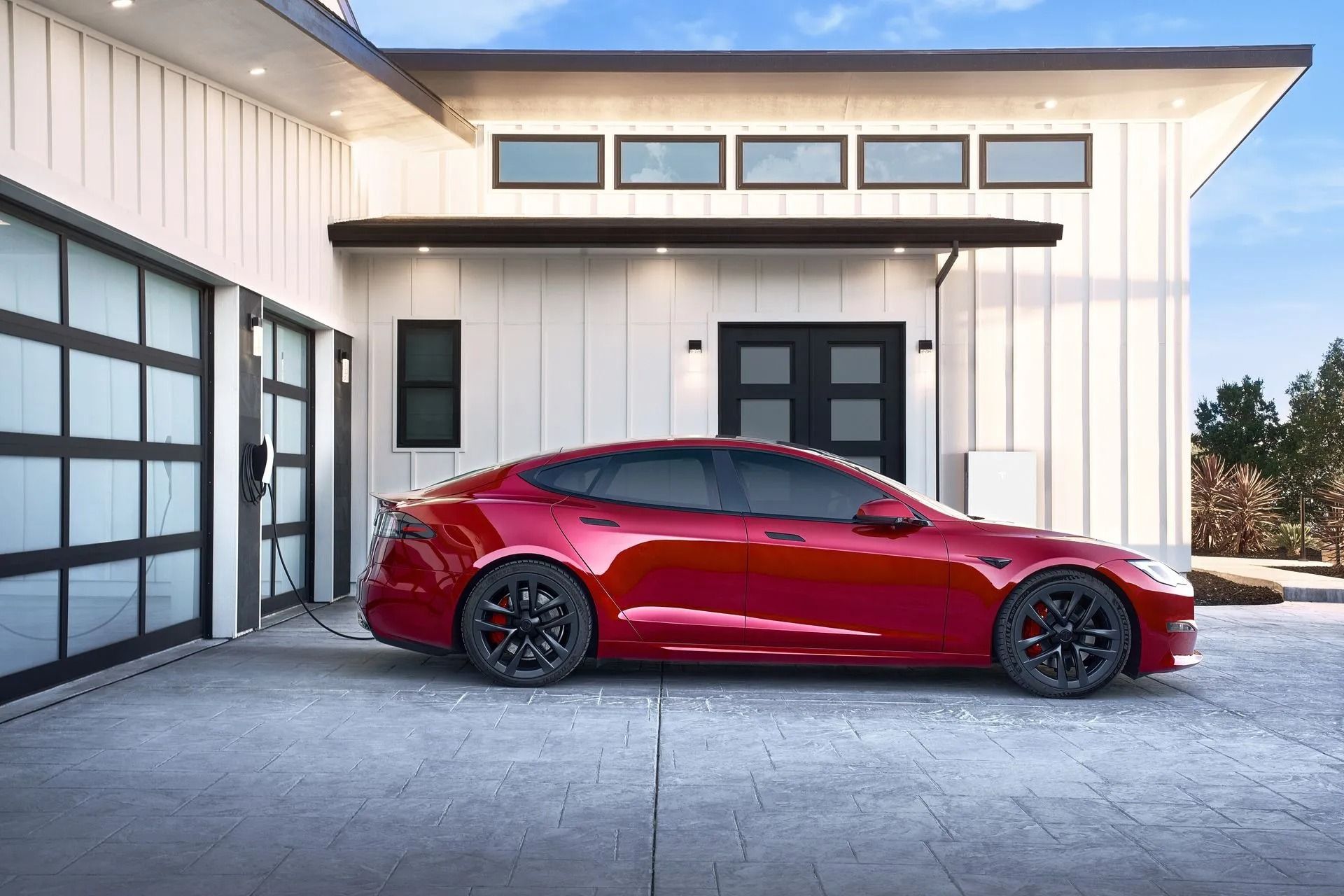 Red sports car parked in front of a modern white house and garage.