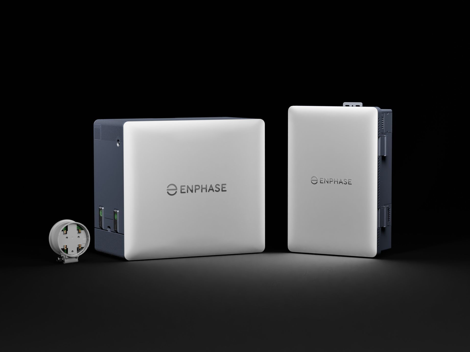 Two Enphase solar battery units on a black background, with a coin for scale
