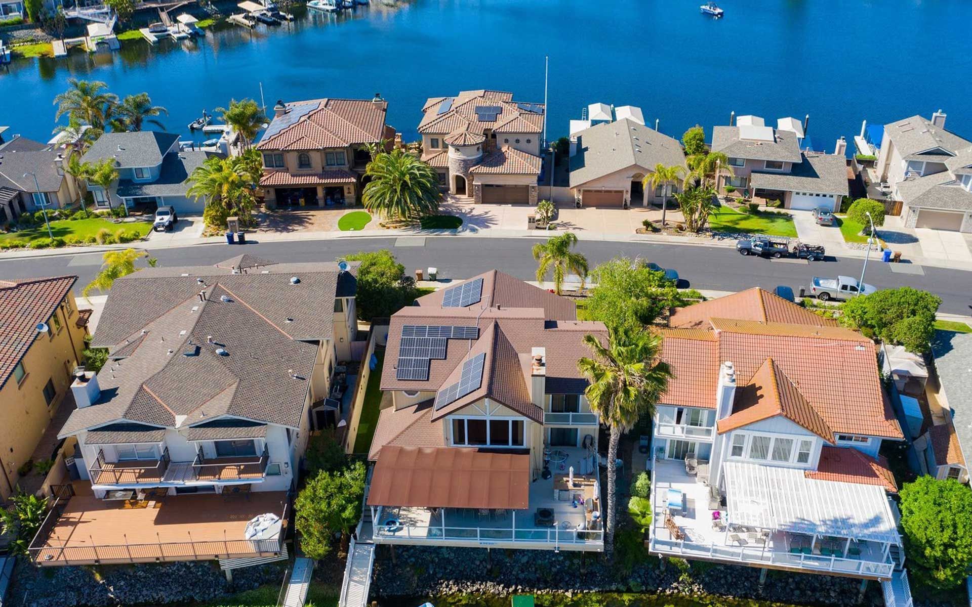 Aerial view of waterfront homes with docks and a calm blue canal.
