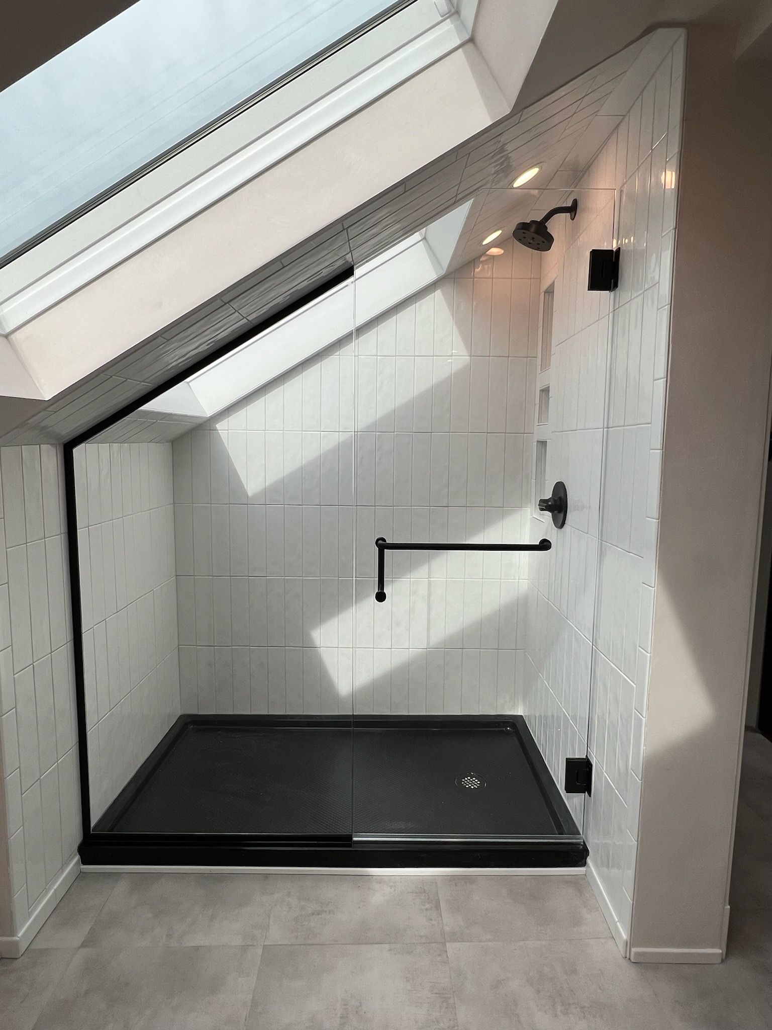 A bathroom with a walk in shower under a skylight.