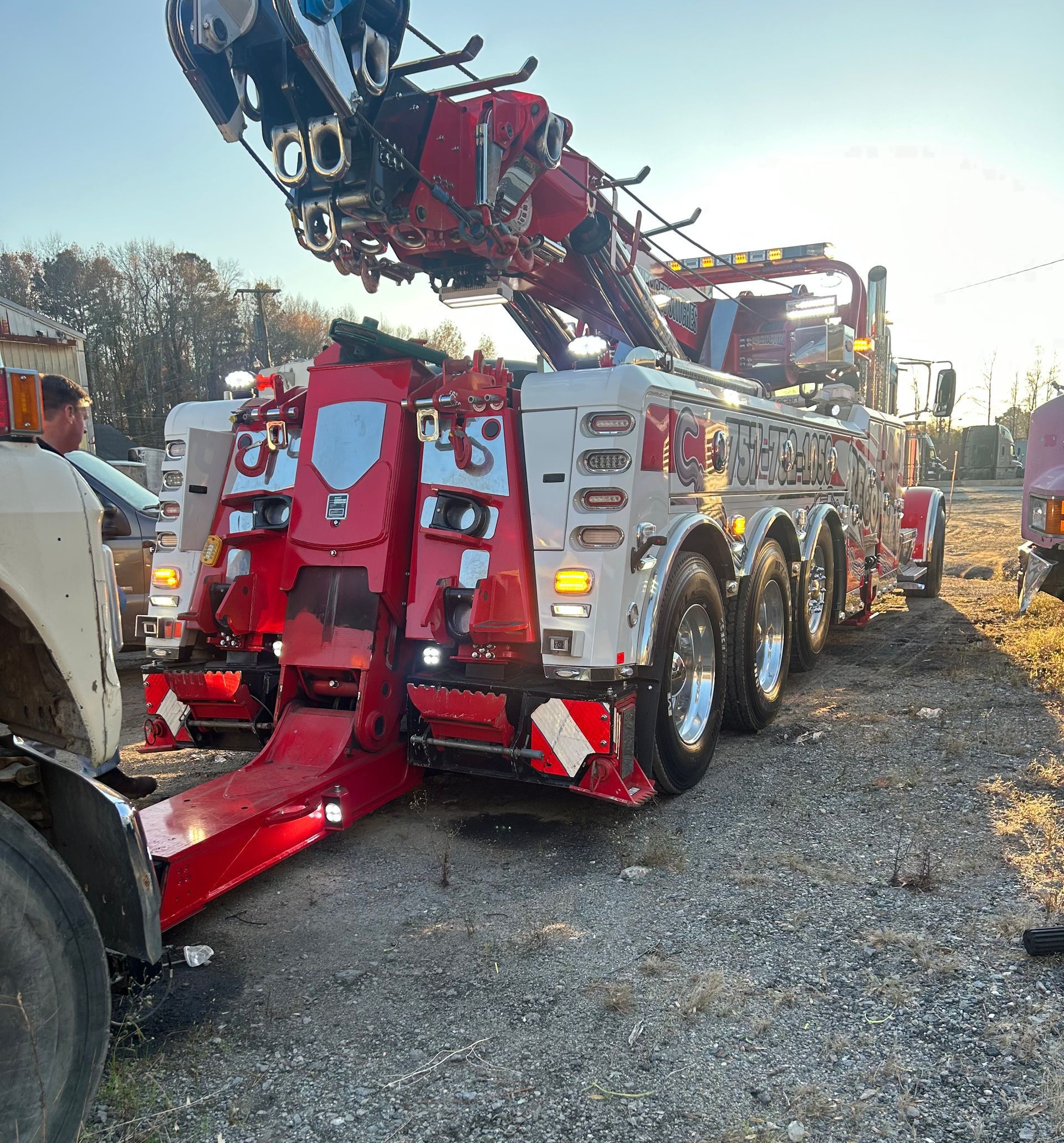 A large, red and white heavy-duty wrecker tow truck parked on a gravel lot during the day.