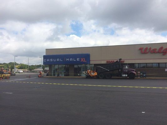 Paved parking lot with construction near a store.  A Casual Male XL and Walgreens are visible under a cloudy sky.