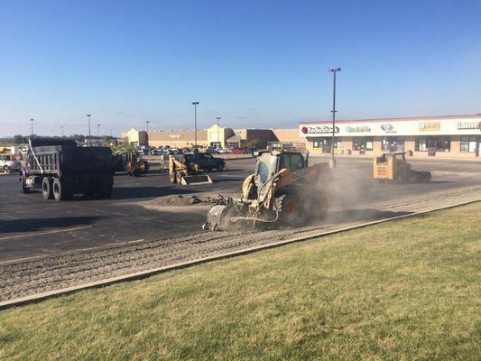 Construction site: Asphalt milling machine, dump truck, and other equipment on a parking lot.