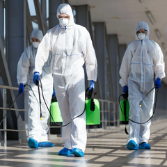 A group of people wearing protective suits and masks is spraying chemicals.