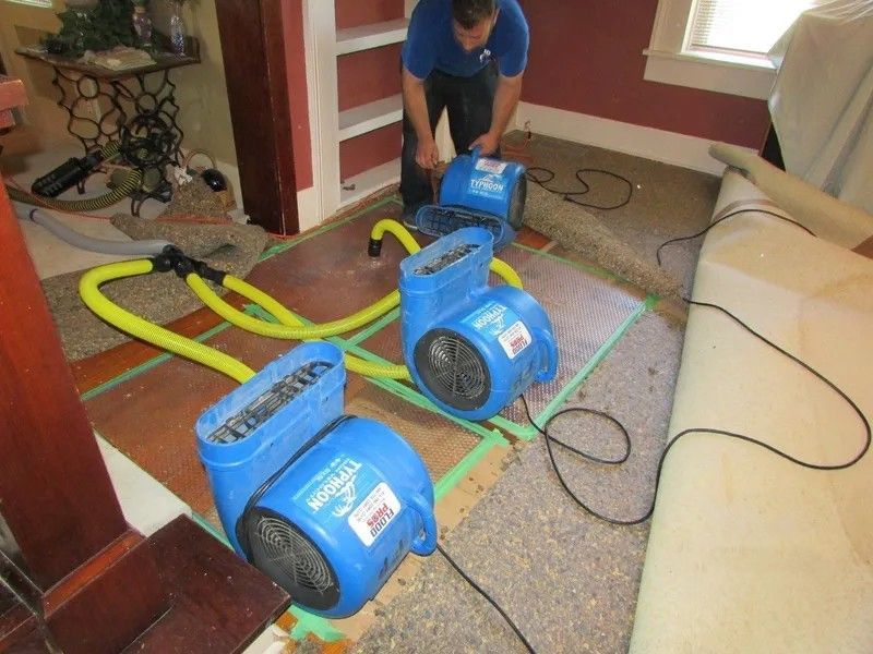 A man in a blue shirt is working on a carpet dryer.