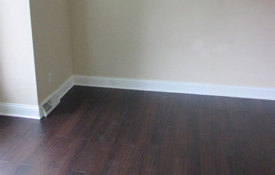 An empty room with hardwood floors and white trim.