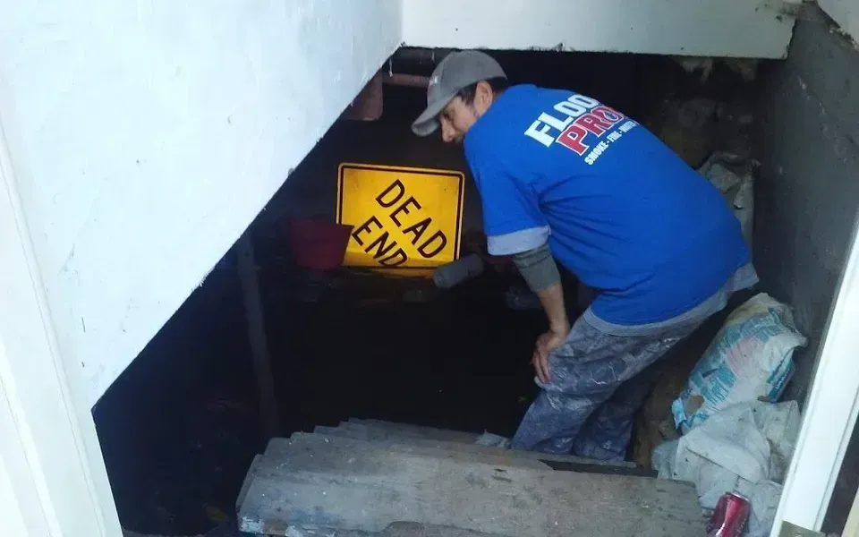 Worker looking at the basement flood damage.