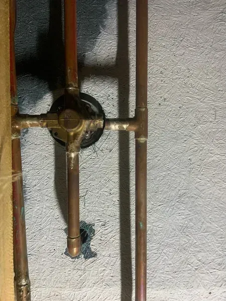 A close up of a copper pipe on a wall.