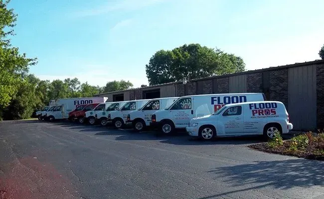 A row of flood pro vans parked in front of a building.