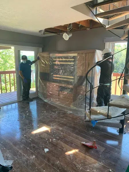 A couple of men are standing in a living room with a spiral staircase.
