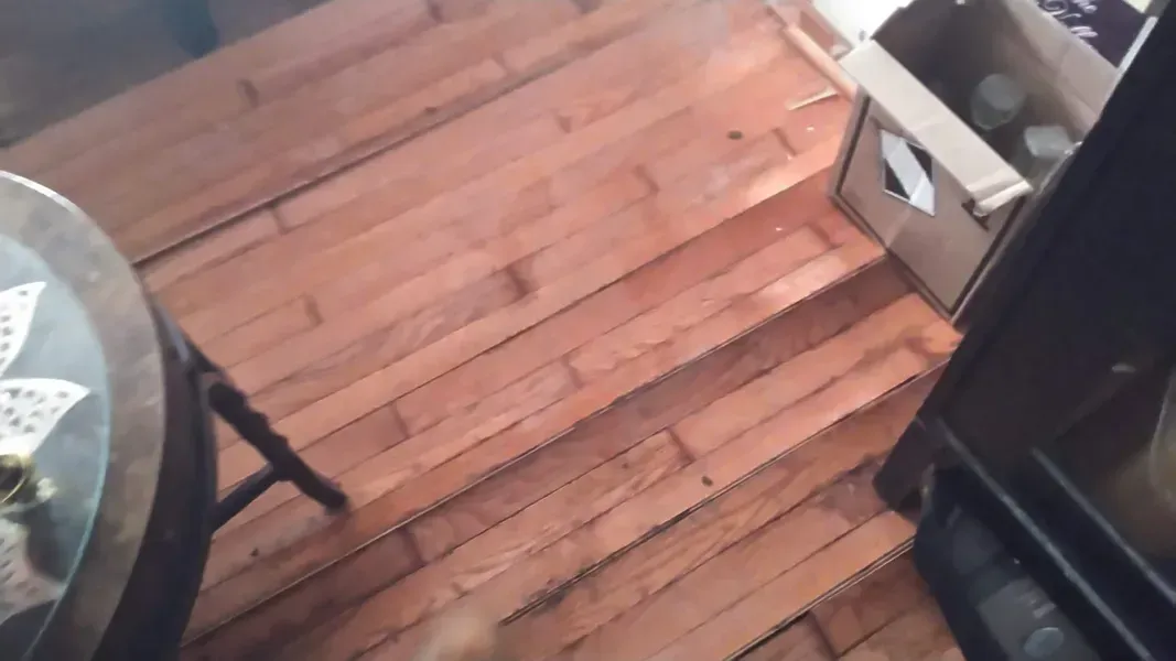 A wooden floor with a table in the background.