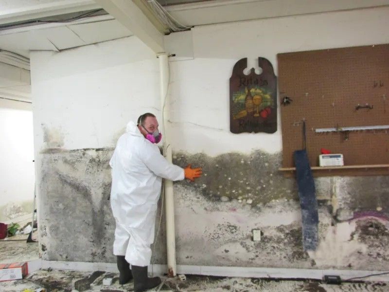 A man in a protective suit is working on a wall.