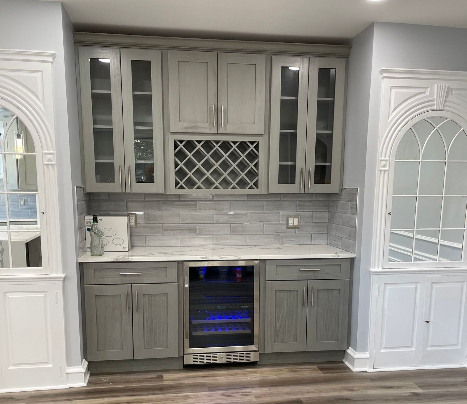 A kitchen with gray cabinets and a wine cooler.
