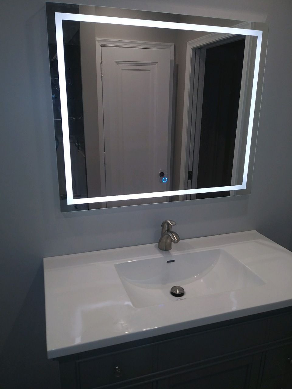 A bathroom sink with a lighted mirror above it.