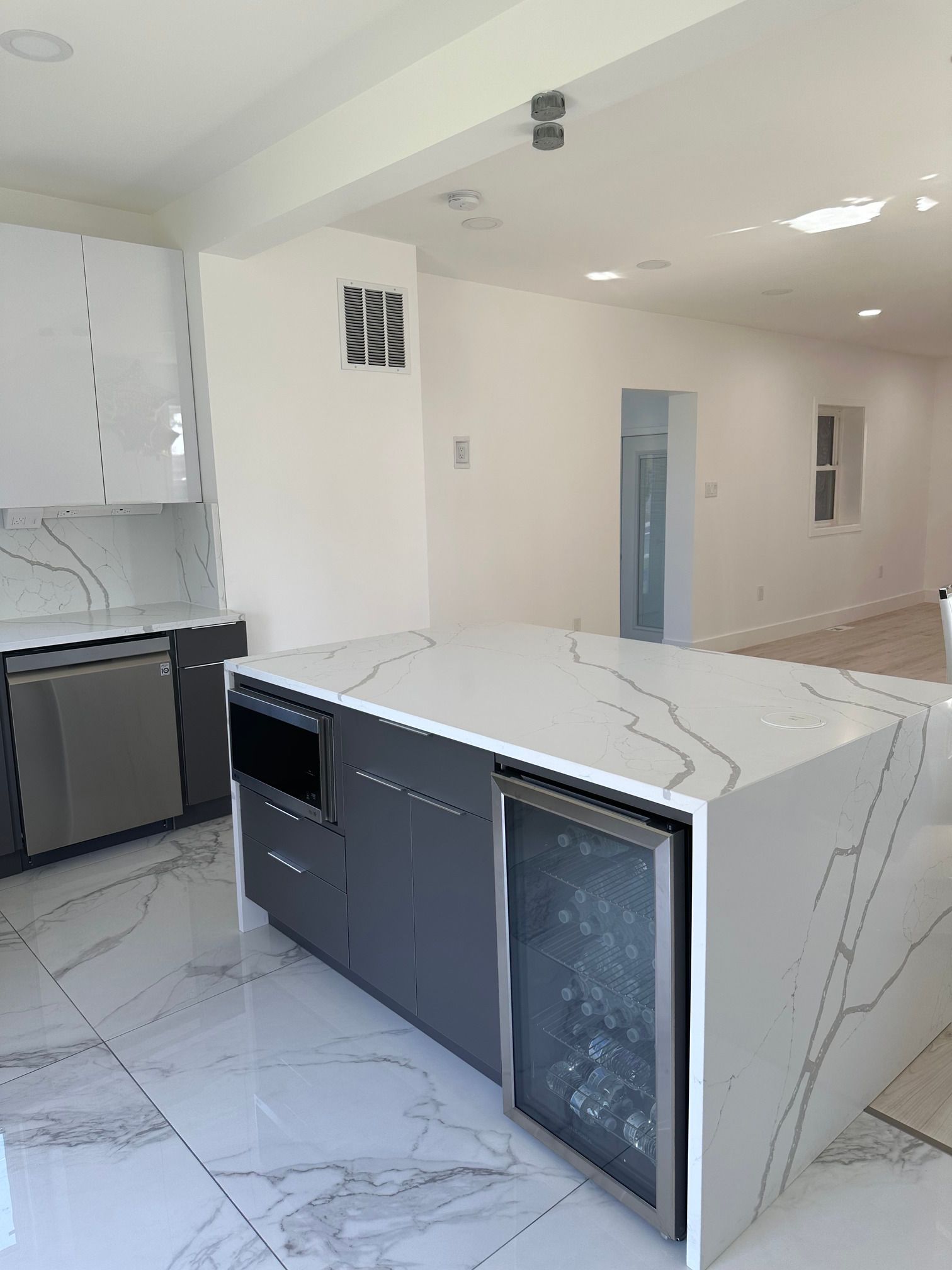A kitchen with a large island and a wine cooler.