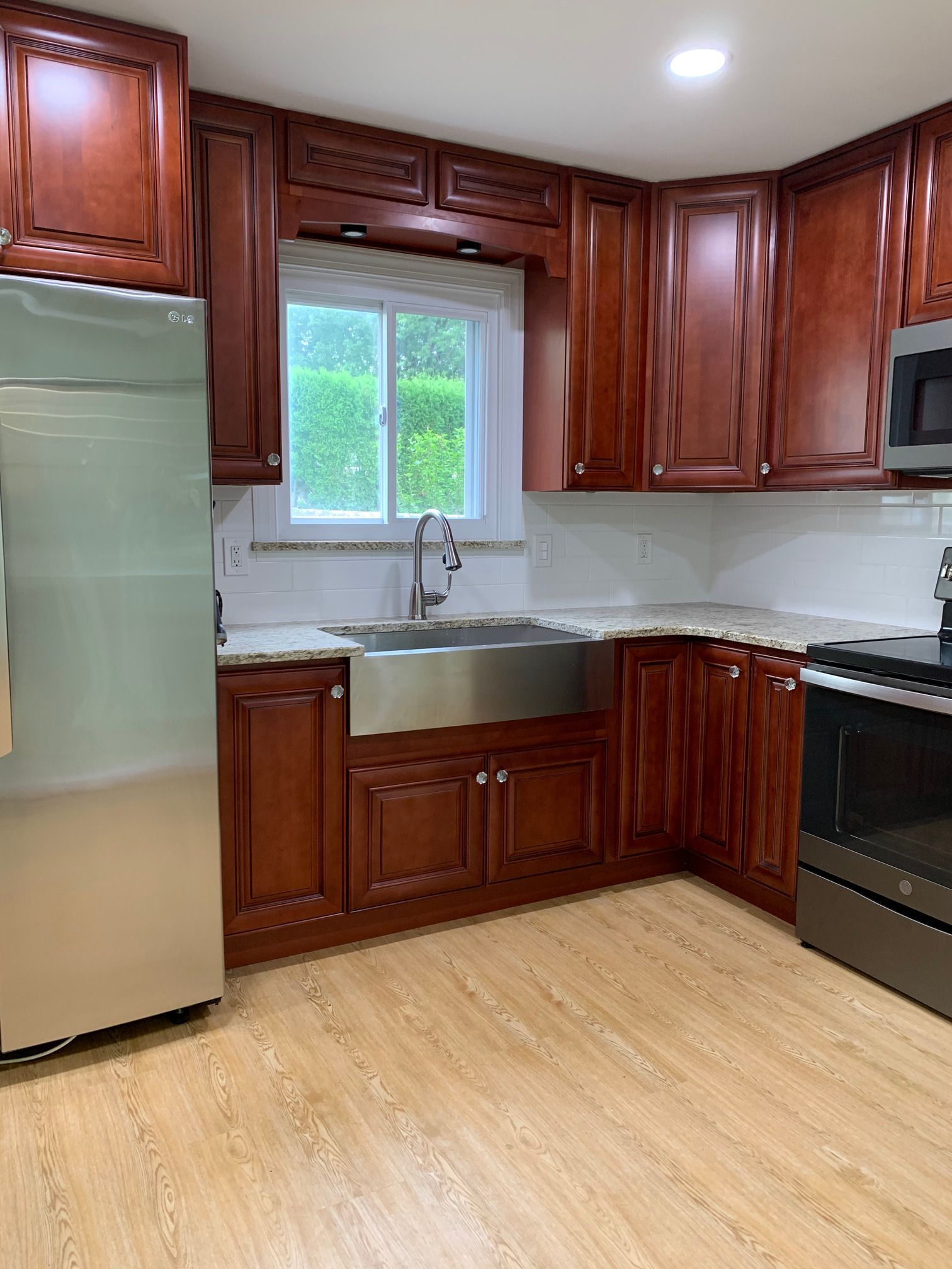 A kitchen with wooden cabinets , stainless steel appliances , a sink and a window.