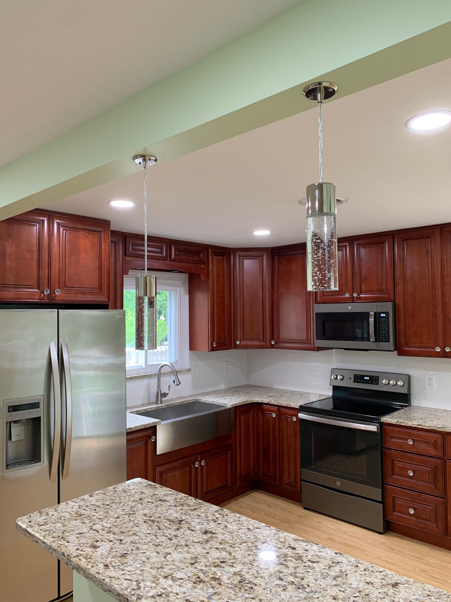 A kitchen with stainless steel appliances , granite counter tops , wooden cabinets and a stainless steel refrigerator.