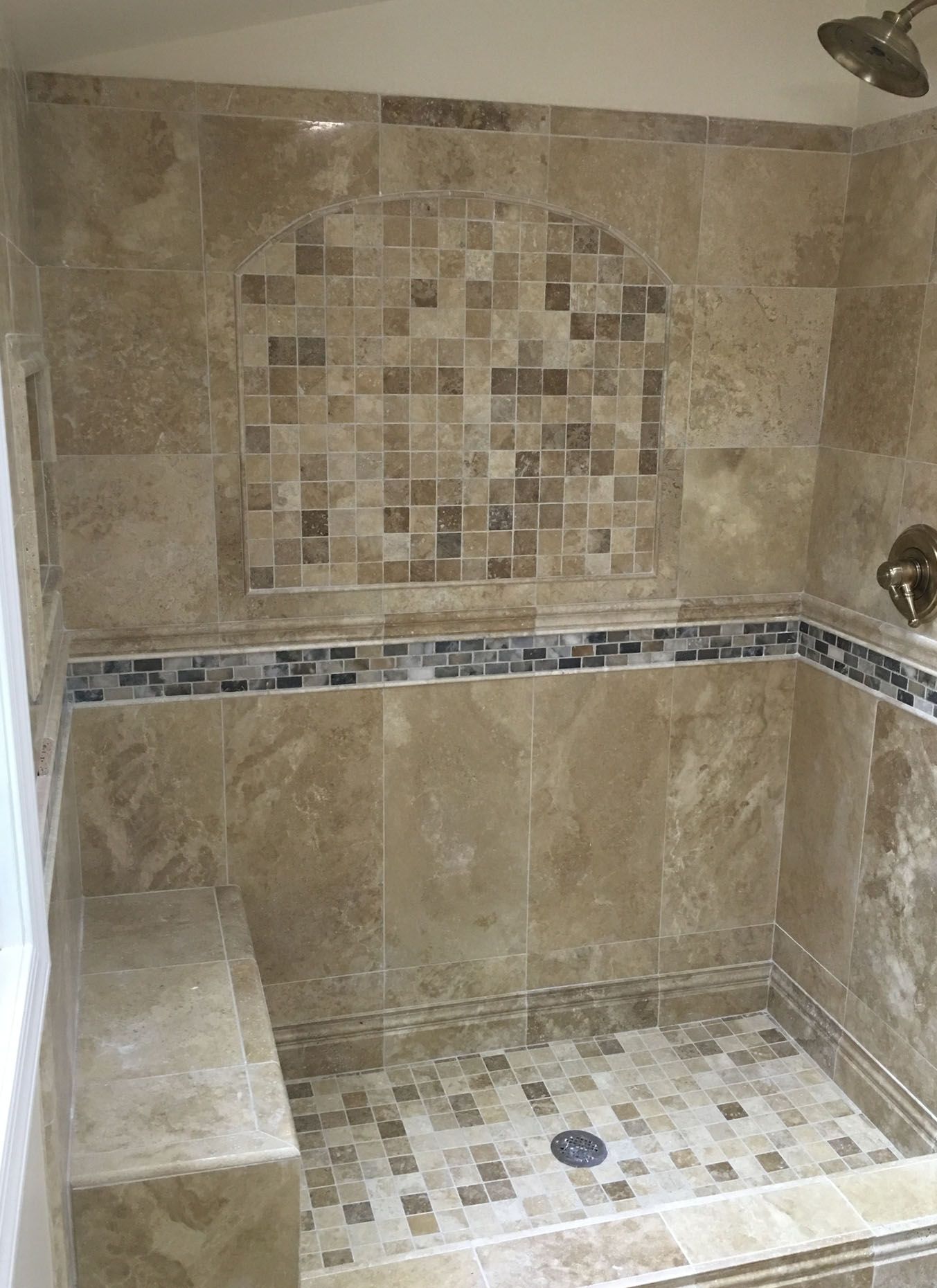 A bathroom with a walk in shower and a bench.