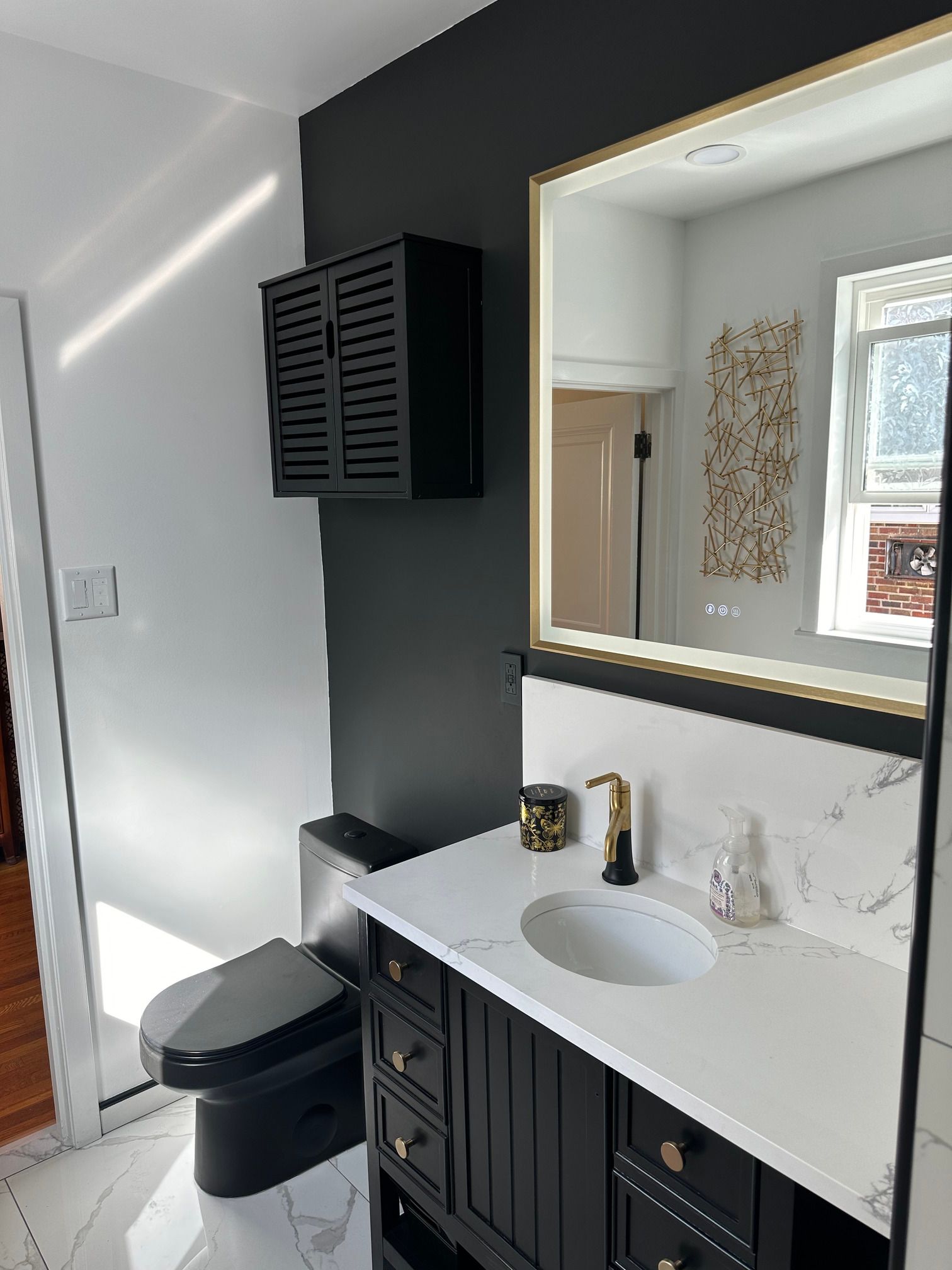 A bathroom with a toilet , sink , mirror and cabinet.