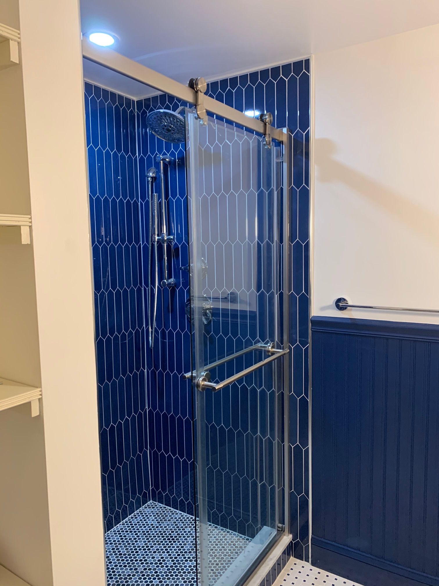 A bathroom with blue tiles and a sliding glass shower door.