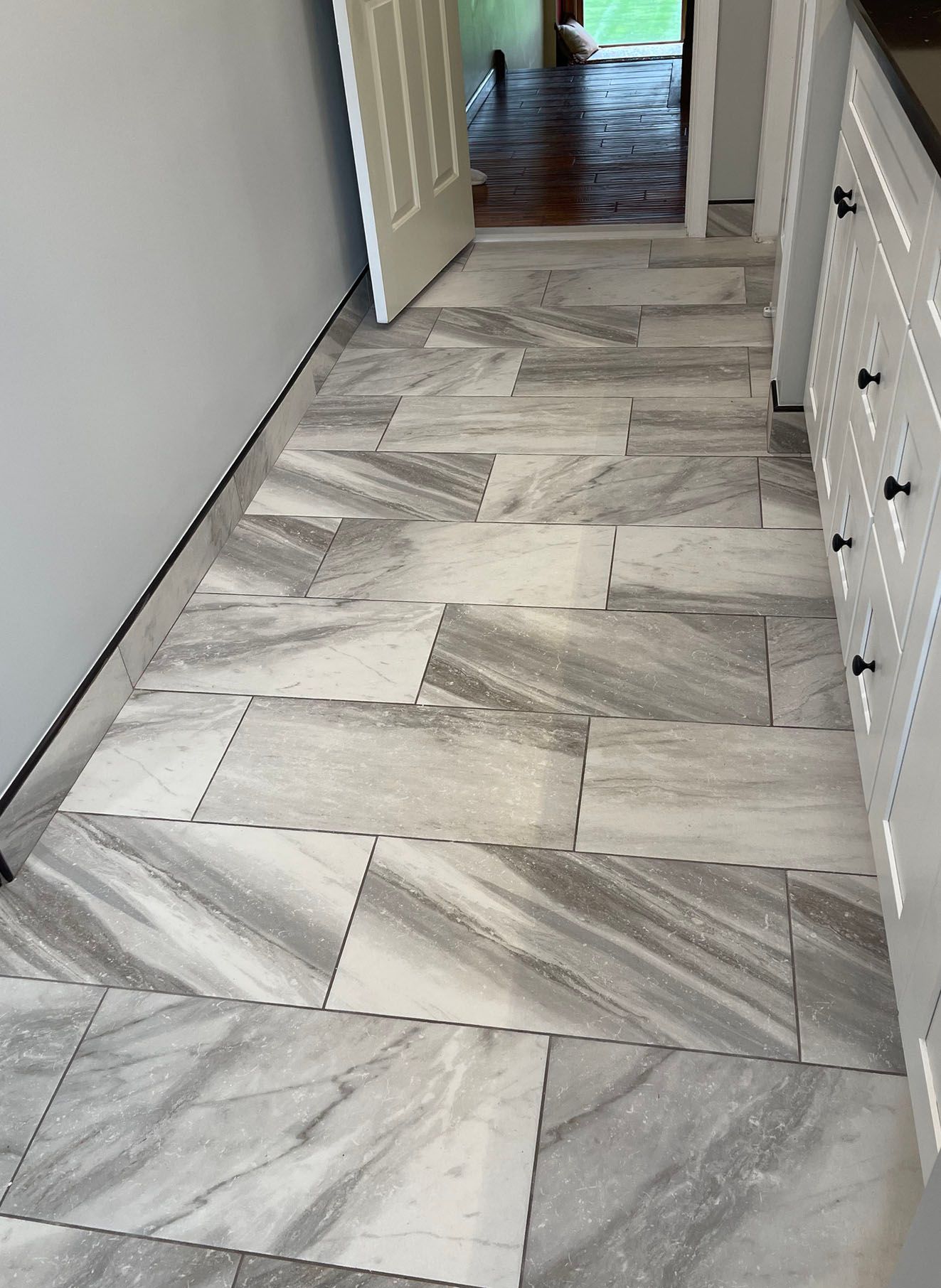 A hallway with gray and white tiles and a door.