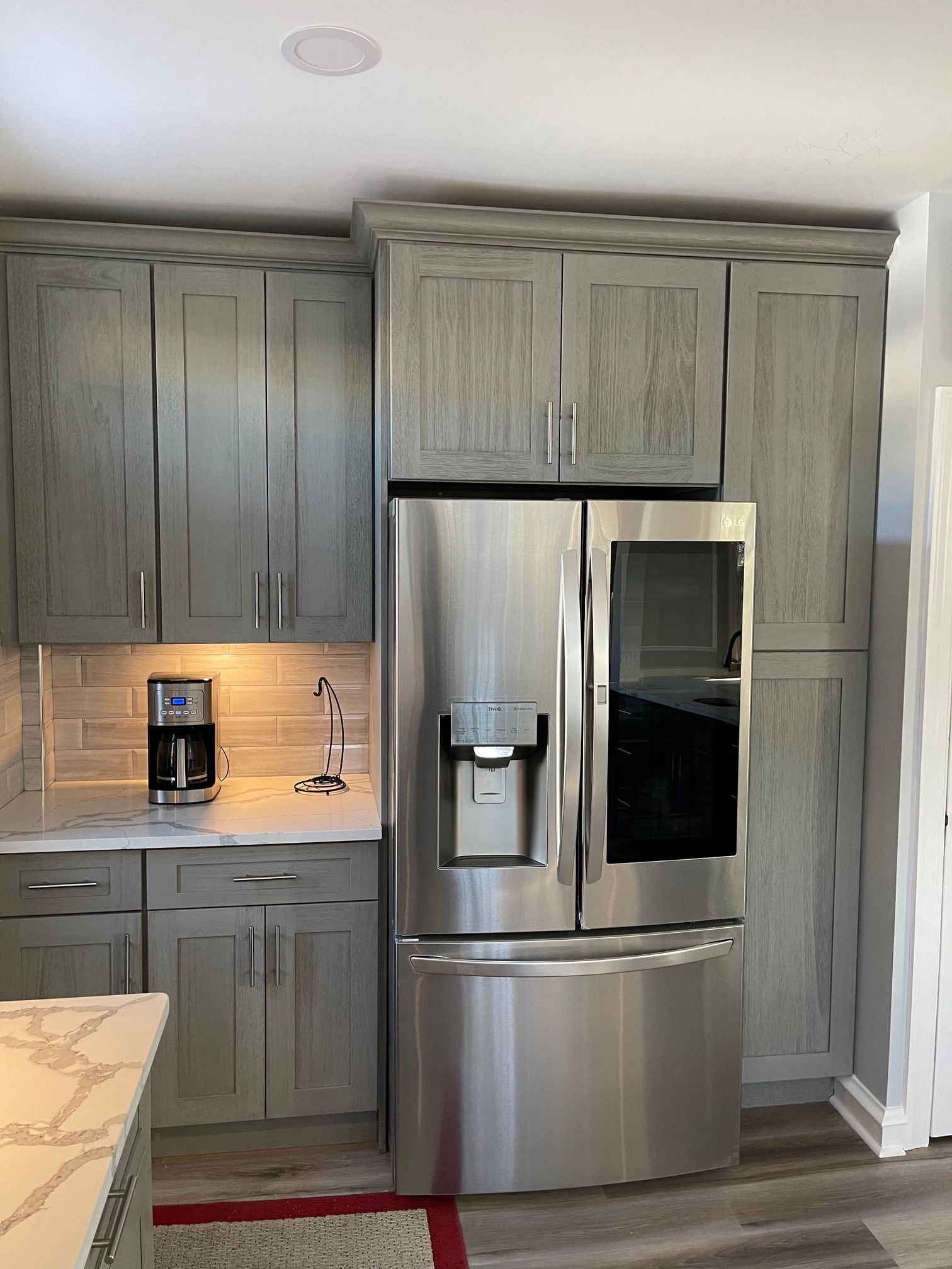 A kitchen with gray cabinets and a stainless steel refrigerator