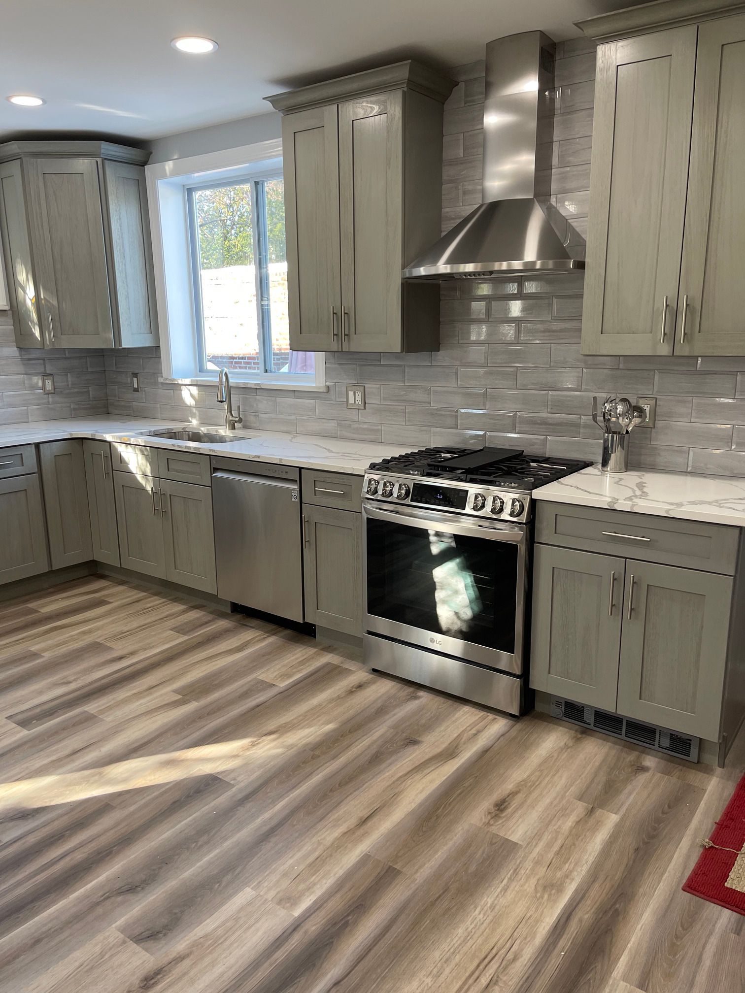 A kitchen with stainless steel appliances and gray cabinets.