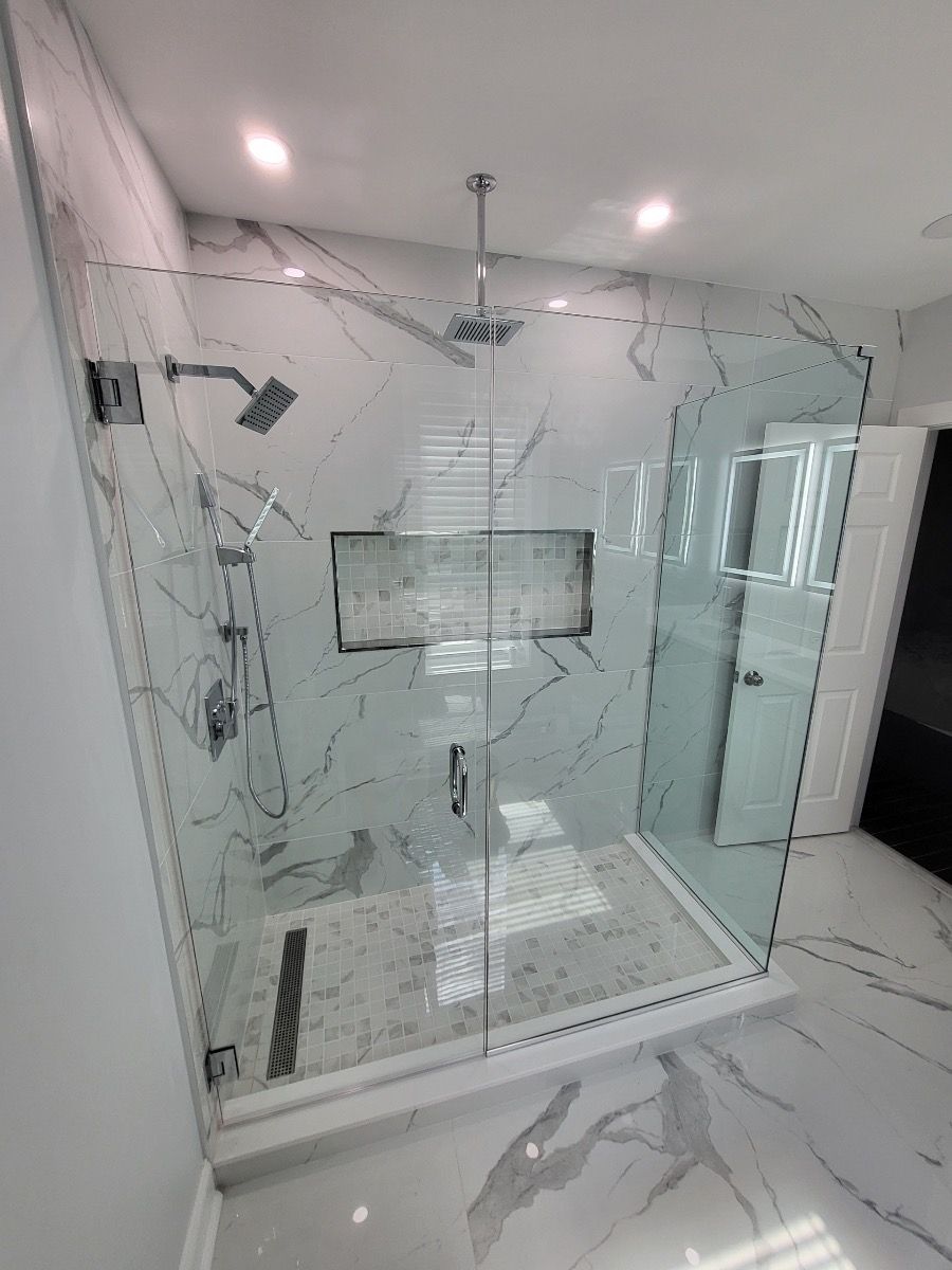 A bathroom with a walk in shower with a glass door.