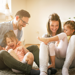 A family is sitting on the floor playing with their children