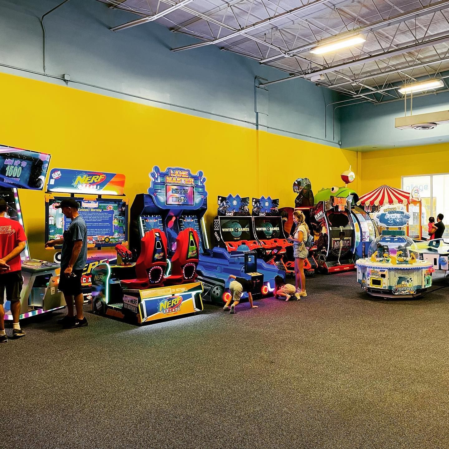 a group of people are playing arcade games in an amusement park
