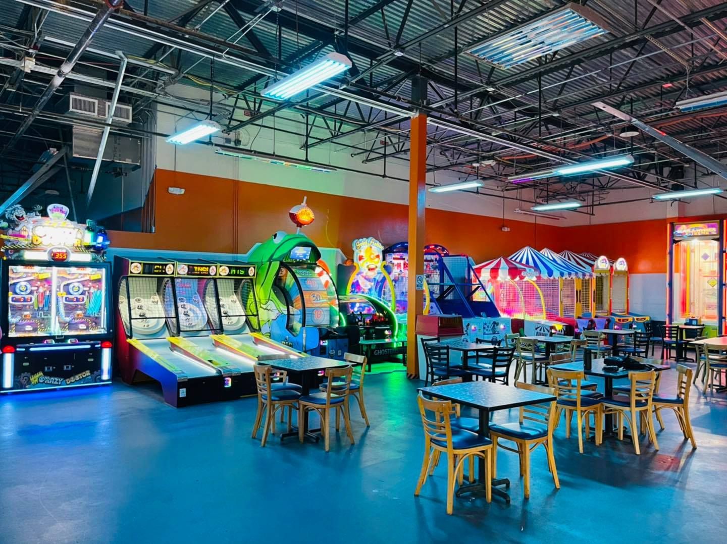 a large room filled with tables and chairs and a bunch of arcade games