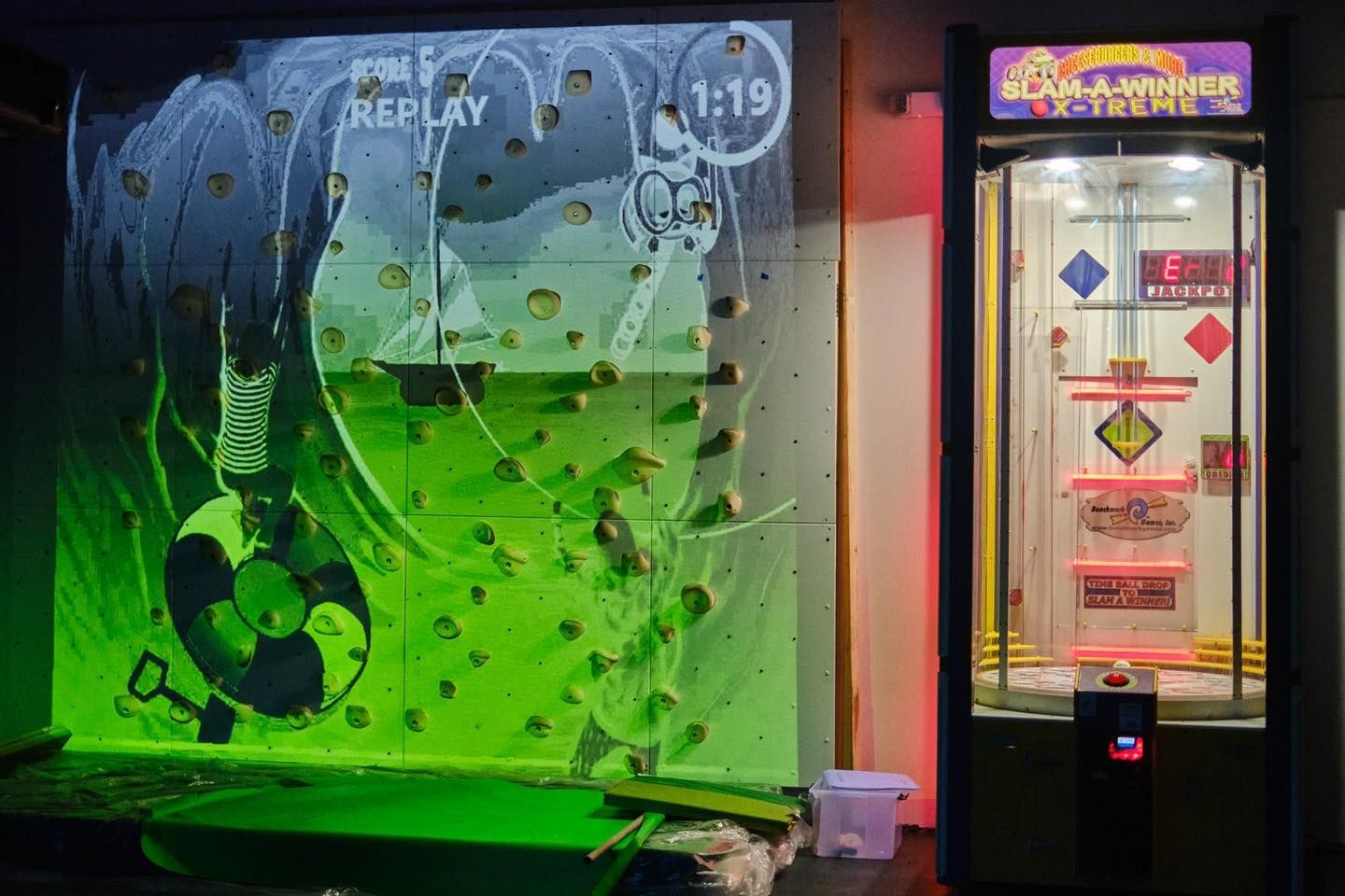 a climbing wall with a soccer ball on it and a game machine in front of it