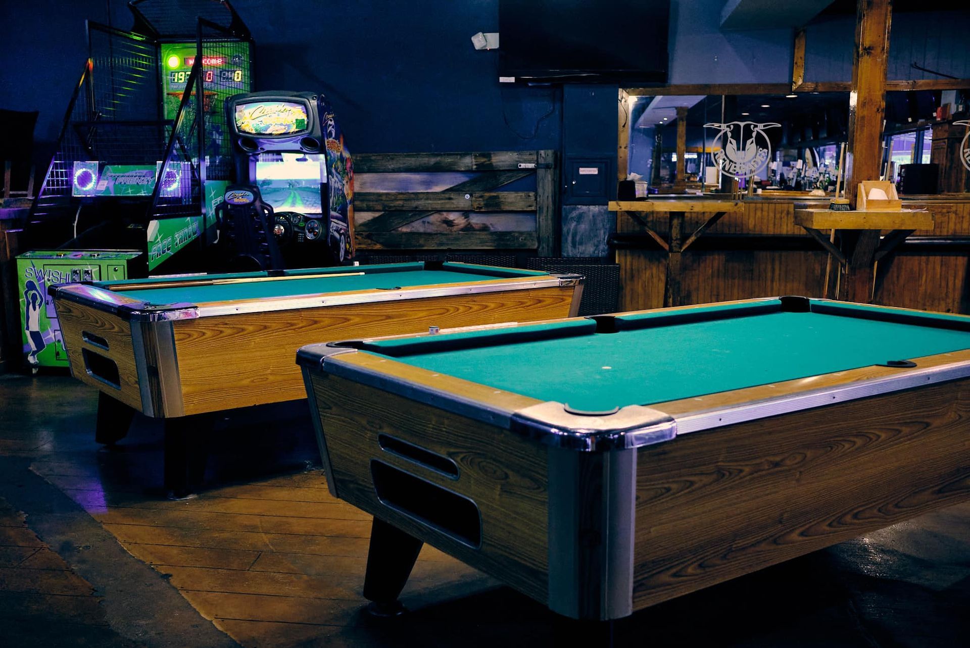 two pool tables are in a room with arcade games