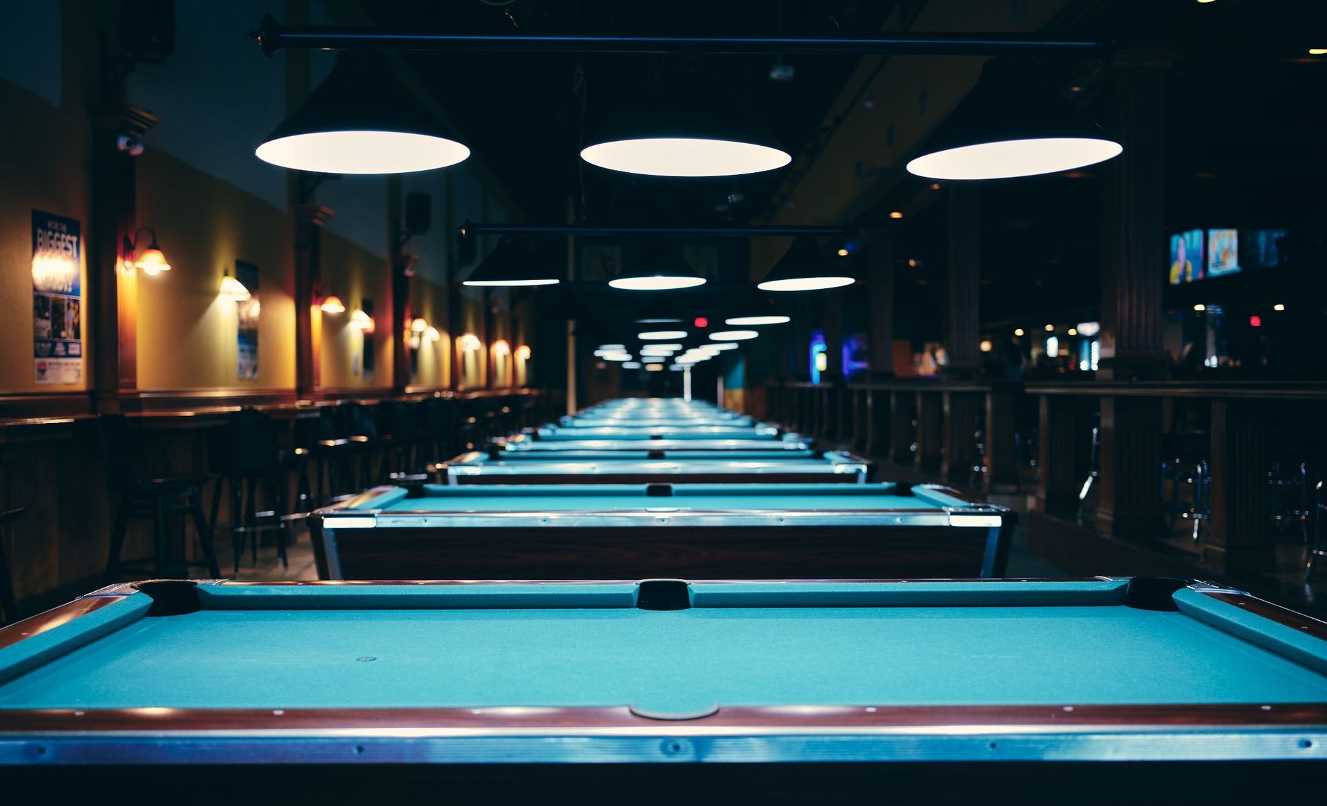a long row of pool tables in a pool hall