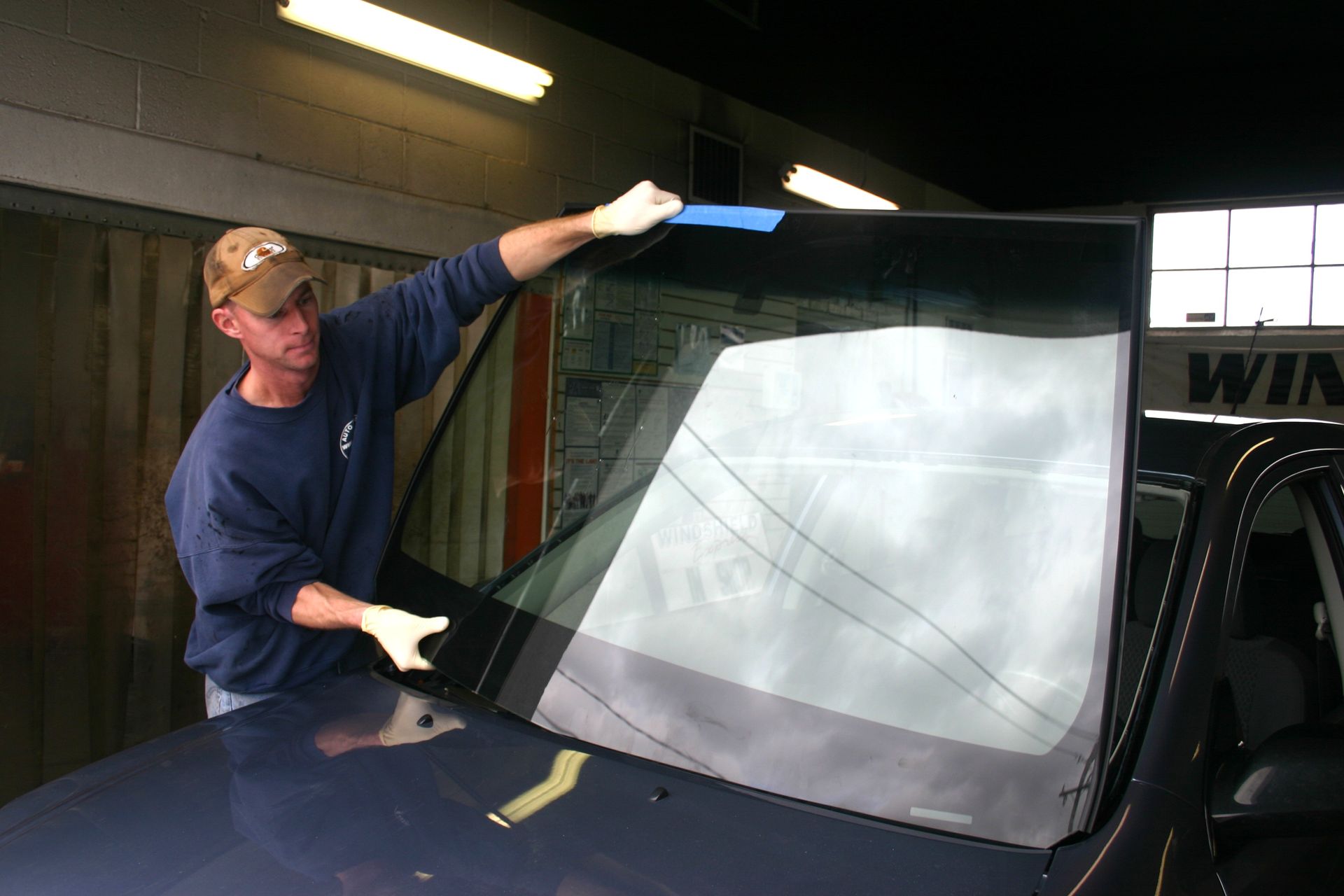Person installing a windshield on a vehicle in a garage