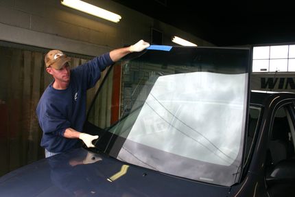 Person installing a windshield on a vehicle in a garage