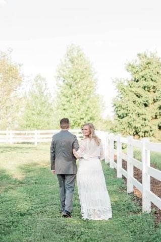 Groom and bride strolling along a fence