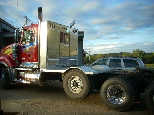 a red semi truck is parked next to a silver suv