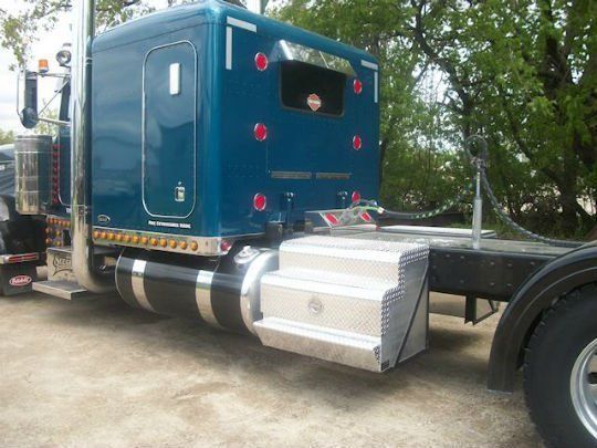a blue semi truck is parked on the side of the road .