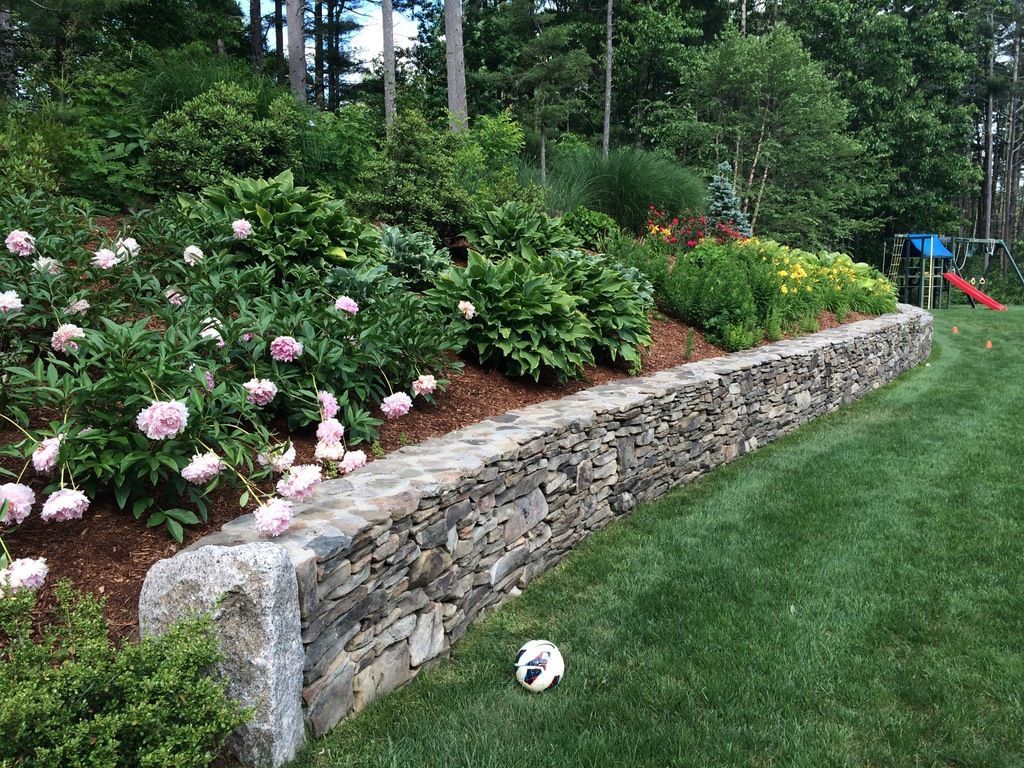 A stone wall surrounded by flowers and shrubs in a garden