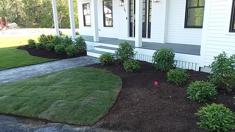 A white house with a porch and a lush green lawn
