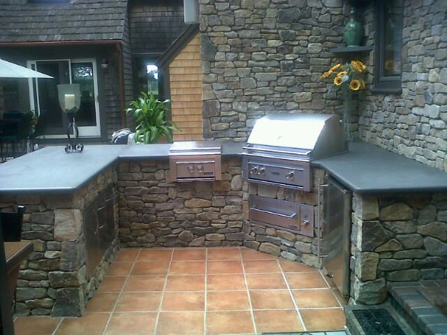 An outdoor kitchen with a grill and a stone wall