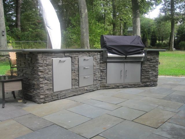 An outdoor kitchen with a grill and a black cover