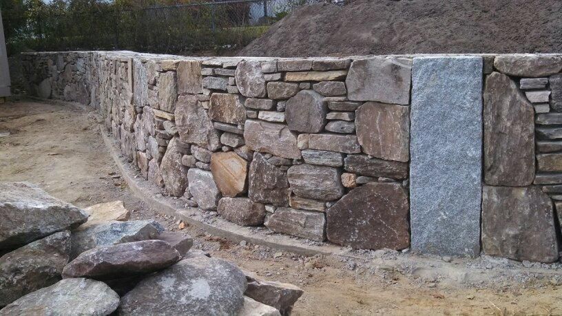 A stone wall is being built on top of a dirt hill