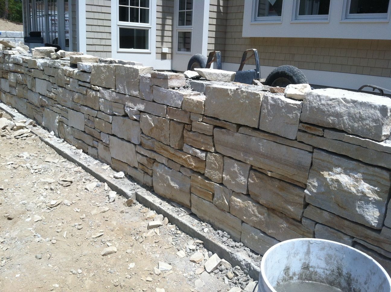 A stone wall is being built in front of a house