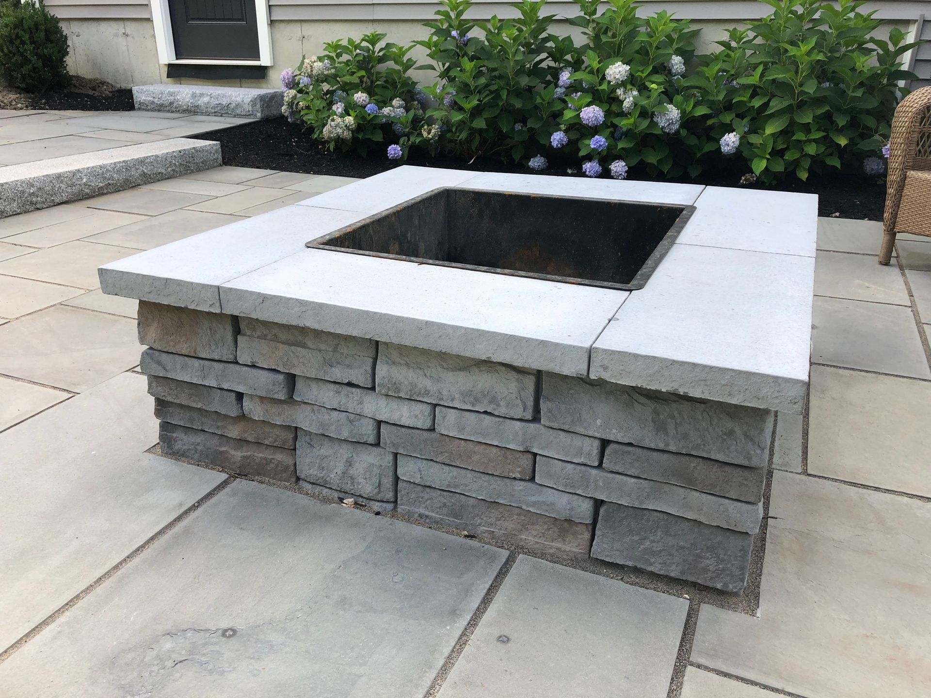A fire pit is sitting on a patio in front of a house